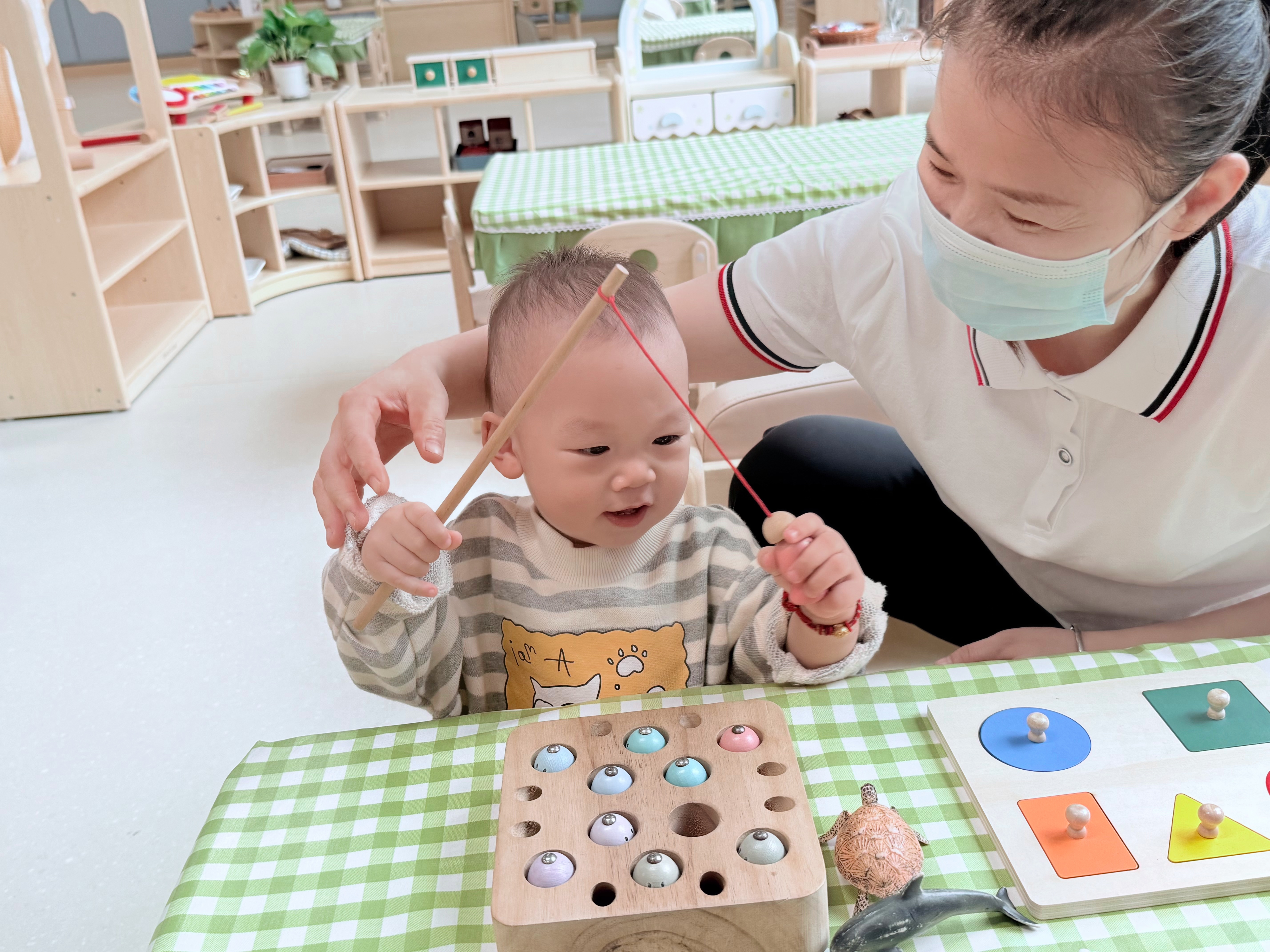 青山湖区托育服务中心里,保育员正在陪孩子做游戏。(本报全媒体记者 陈璋).jpg